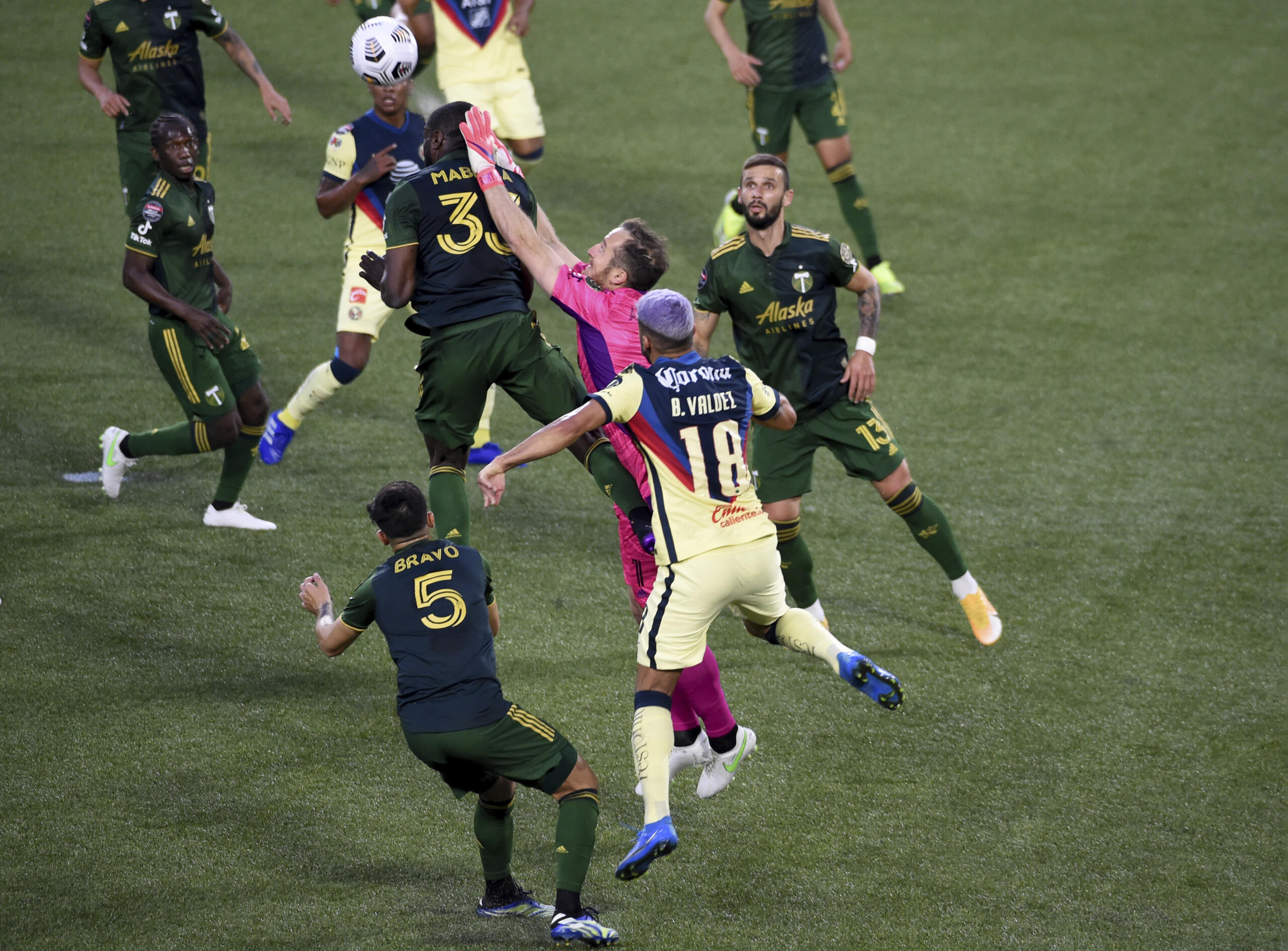 Portland Timbers goalkeeper Jeff Attinella, center, punches the ball away as Larrys Mabiala, left, and América defender Bruno Valdez, right, close in during the first half of a CONCACAF Champions League soccer match in Portland, Ore., Wednesday, April 28, 2021.