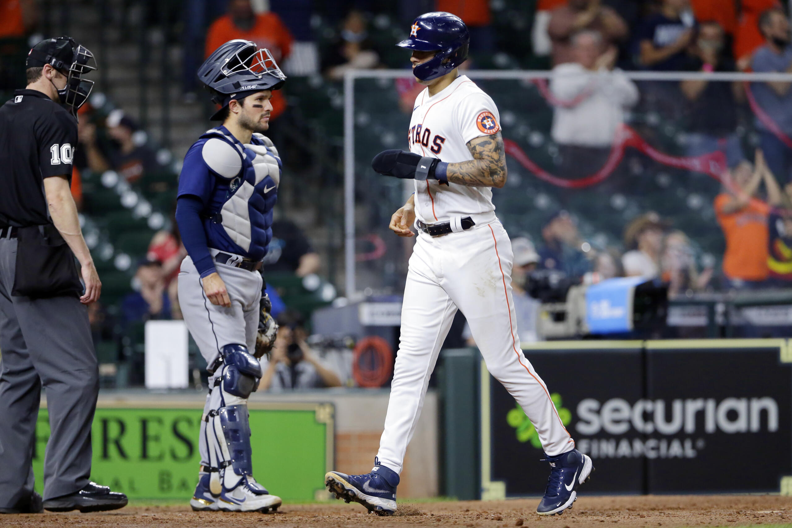 Houston Astros' Carlos Correa, right, crosses the plate in front of Seattle Mariners catcher Luis Torrens, middle, to score the go-ahead run on a walk issued to Myles Straw with the bases loaded during the eighth inning of a baseball game Wednesday, April 28, 2021, in Houston.