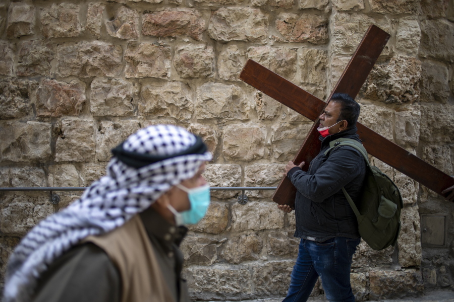 A Christian carries a cross as he walks along the Via Dolorosa towards the Church of the Holy Sepulchre, traditionally believed by many to be the site of the crucifixion of Jesus Christ, during the Good Friday procession in Jerusalem&#039;s old city, Friday, April 2, 2021.