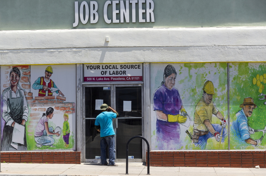 FILE - In this May 7, 2020, file photo, a person looks inside the closed doors of the Pasadena Community Job Center in Pasadena, Calif., during the coronavirus outbreak. While most Americans have weathered the pandemic financially, about 38 million say they are worse off now than before the outbreak began in the U.S. According to a new poll from Impact Genome and The Associated Press-NORC Center for Public Affairs Research 55% of Americans say their financial circumstances are about the same now as a year ago, and 30% say their finances have improved.