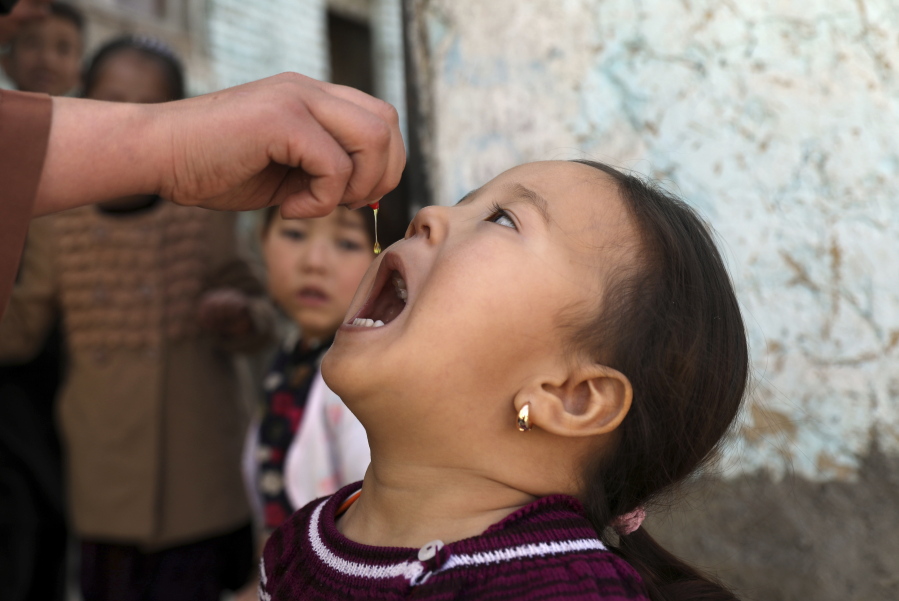 Shabana Maani, gives a polio vaccination to a child in the old part of Kabul, Afghanistan, Monday, March 29, 2021. Afghanistan is inoculating millions of children against polio after pandemic lockdowns stalled the effort to eradicate the crippling disease. But the recent killing of three vaccinators points to the dangers facing the campaign.