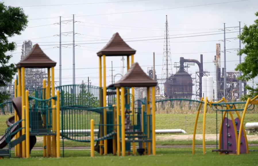 FILE - In this Monday, March 23, 2020 file photo, a playground outside the Prince Hall Village Apartments sits empty near one of the petrochemical facilities in Port Arthur, Texas. According to a study published Wednesday, April 28, 2021 in the journal Science Advances,  across America, people of color are disproportionately exposed to air pollution from industry, vehicles, construction and many other sources. (AP Photo/David J.