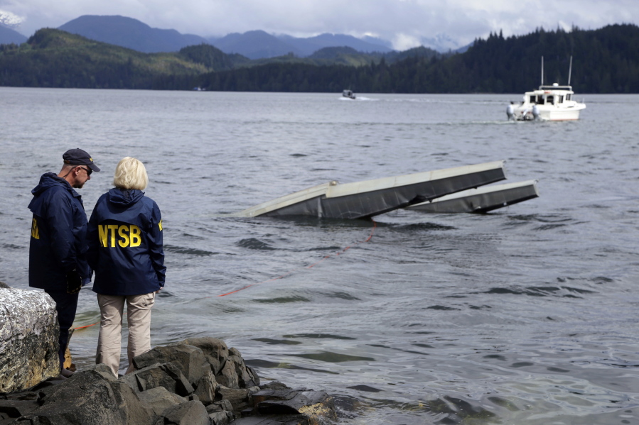 FILE - In this photo provided by the National Transportation Safety Board, NTSB investigator Clint Crookshanks, left, and member Jennifer Homendy stand near the site of some of the wreckage of the DHC-2 Beaver, Wednesday, May 15, 2019, that was involved in a midair collision near Ketchikan, Alaska, a couple of days earlier.  The pilots of two Alaskan sightseeing planes that collided in midair couldn't see the other aircraft because airplane structures or a passenger blocked their views, and they didn't get electronic alerts about close aircraft because safety systems weren't working properly. That's what the staff of the National Transportation Safety board found in their investigation.