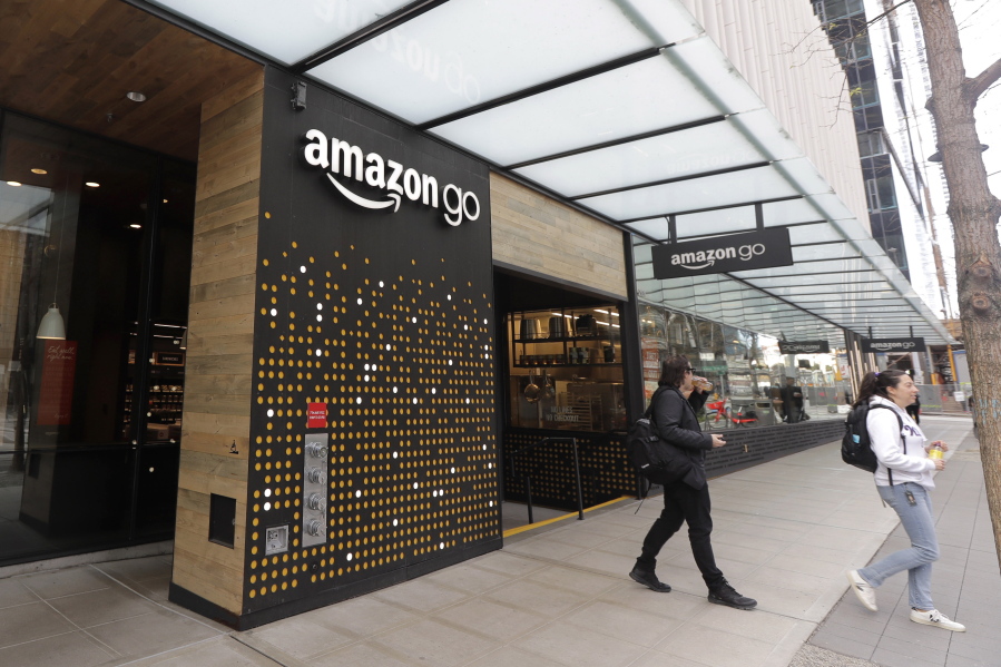 FILE - In this March 4, 2020 file photo, people walk out of an Amazon Go store, in Seattle.  Amazon said Wednesday, April 21, 2021 that it is rolling out its pay-by-palm technology to some of its Whole Foods supermarkets. The technology, called Amazon One, lets shoppers scan the palm of their hand and connect it to their credit card or Amazon accounts. (AP Photo/Ted S.