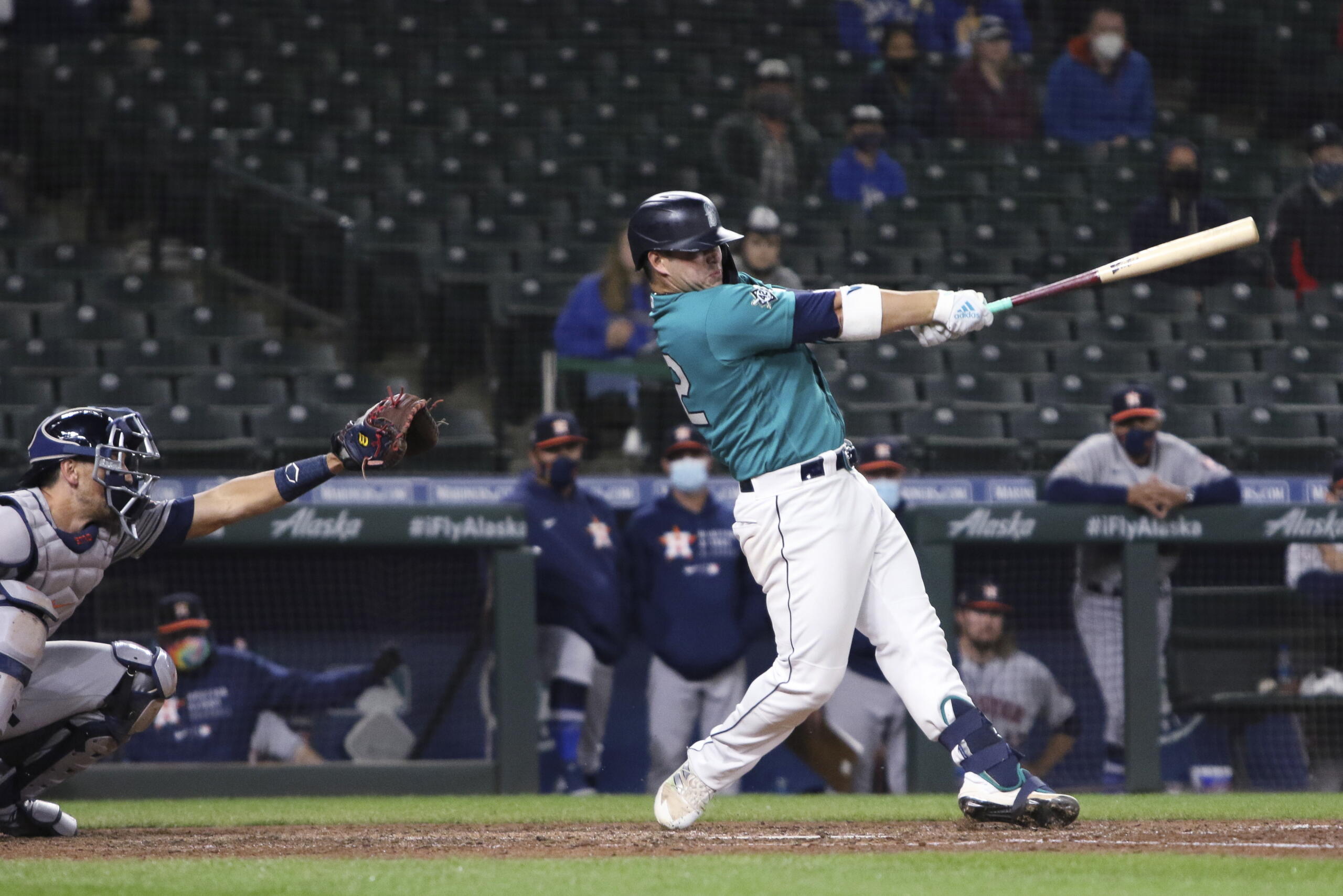 Seattle Mariners' Ty France follows through on a single that drove in the winning run, next to Houston Astros catcher Jason Castro during the ninth inning of a baseball game Friday, April 16, 2021, in Seattle. The Mariners won 6-5.