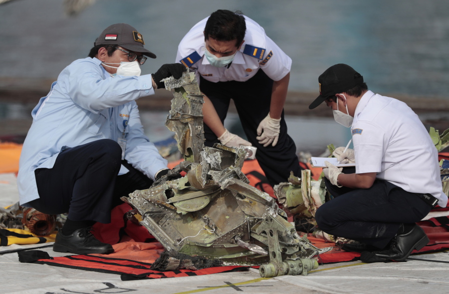 FILE - In this Jan. 21, 2021, file photo, investigators inspect a pieces of the Sriwijaya Air flight SJ-182 retrieved from the Java Sea where the passenger jet crashed on Jan. 9, at Tanjung Priok Port in Jakarta, Indonesia. A lawsuit filed in Seattle against Boeing alleges a malfunctioning autothrottle system on the older 737 jet led to the January crash of the Sriwijaya Air flight that killed all 62 people on board.