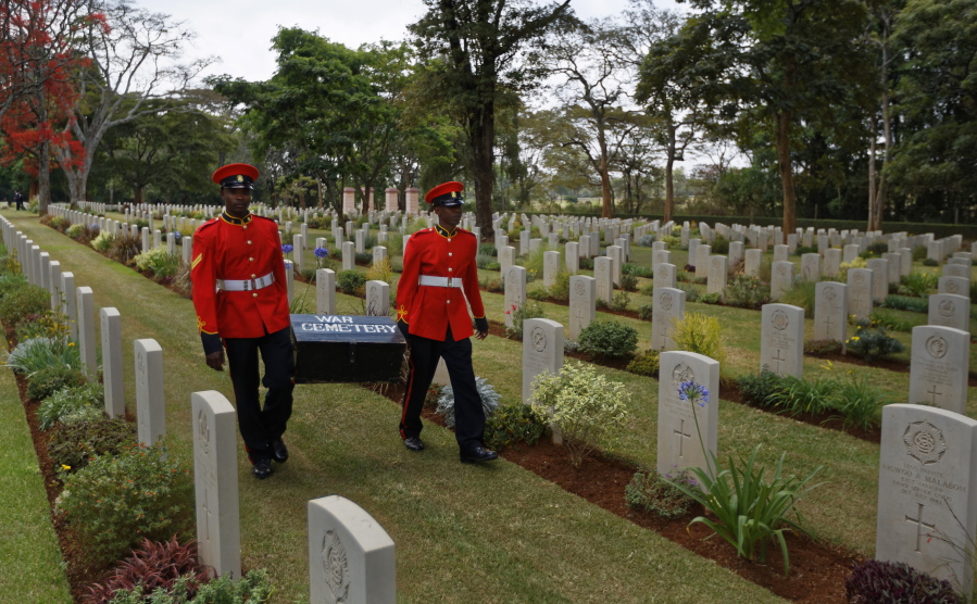 FILE - In this Sunday, Nov. 13, 2016 file photo, two members of Kenya's Military Police walk past graves as they leave after attending a Remembrance Sunday event, to honor the contribution of those British and Commonwealth military who died in the two World Wars and later conflicts, at the Nairobi War Cemetery in Kenya. The Commonwealth War Graves Commission has apologized after an investigation found that at least 161,000 mostly Africans and Indians who died fighting for the British Empire during World War I weren't properly honored due to "pervasive racism", according to findings released Thursday, April 22, 2021.
