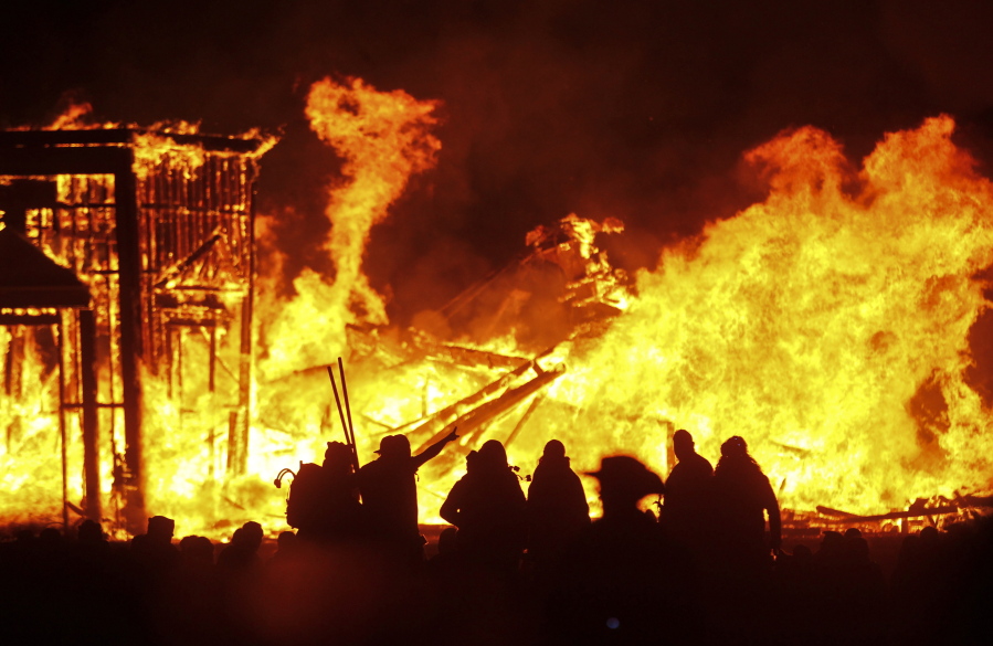 FILE - In this Sept. 3, 2016, file photo, attendees are silhouetted as the structure of the "Man" burns during Burning Man at the Black Rock Desert of Gerlach, Nev., north of Reno. Burning Man organizers announced Tuesday, April 27, 2021, they are canceling this summer's annual counter-culture festival in the Nevada desert for the second year in a row due to the COVID-19 pandemic.