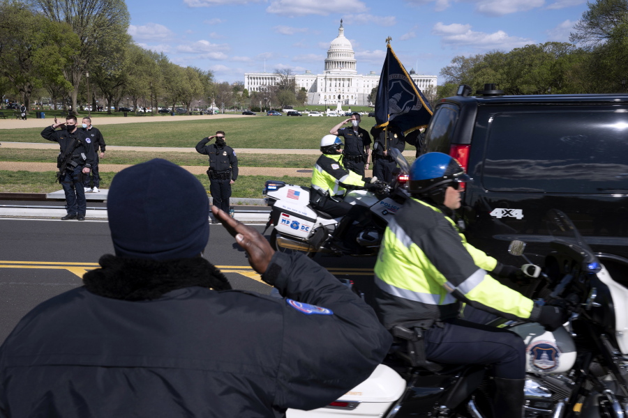 With the U.S. Capitol in the background, U.S. Capitol Police officers salute as procession carries the remains of a U.S. Capitol Police officer who was killed after a man rammed a car into two officers at a barricade outside the Capitol in Washington, Friday, April 2, 2021.