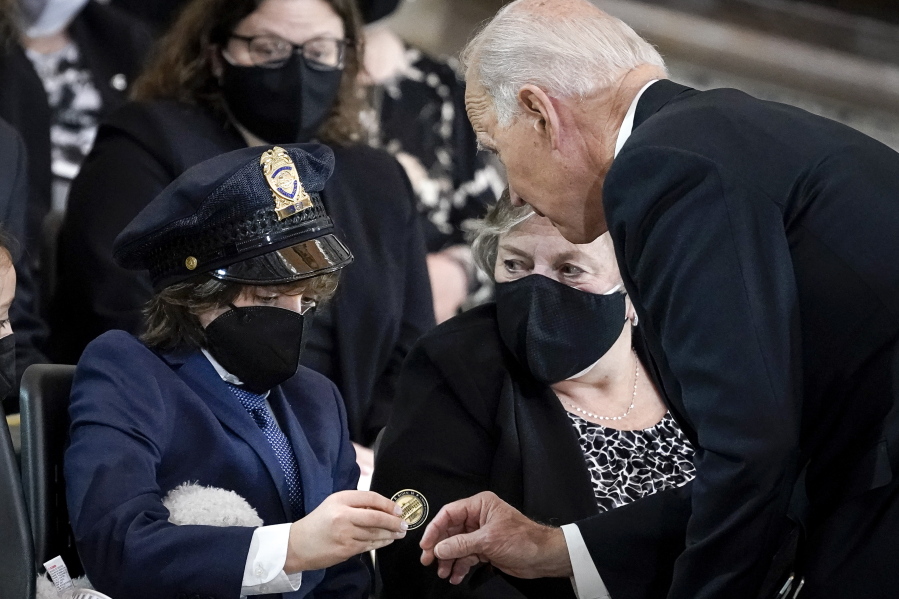 President Joe Biden gives a coin to Logan Evans, son of late U.S. Capitol Police officer William "Billy" Evans, during a memorial service as Evans lies in honor in the Rotunda at the U.S. Capitol, Tuesday, April 13, 2021 in Washington.