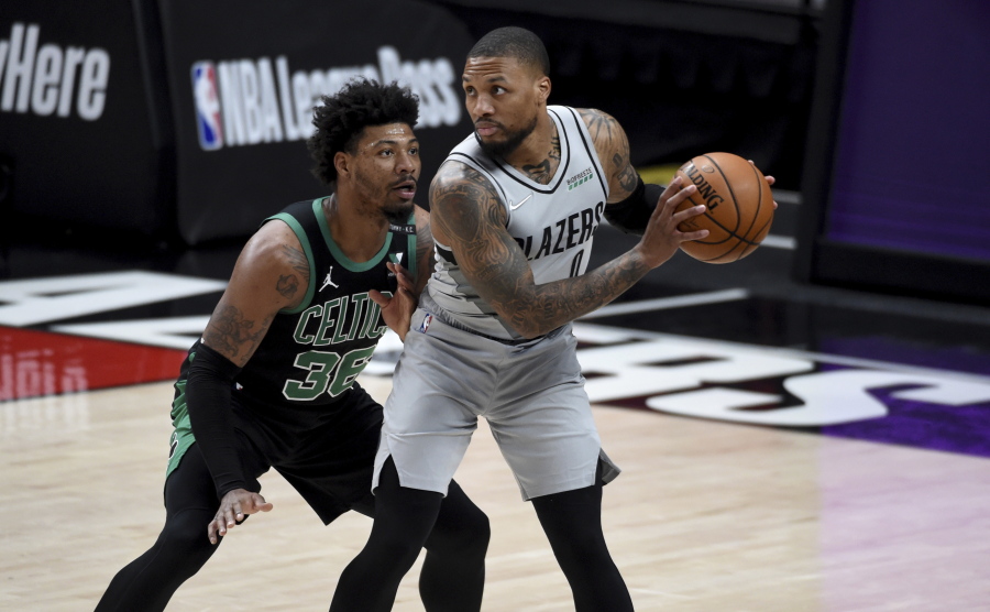 Portland Trail Blazers guard Damian Lillard, right, looks to drive the ball on Boston Celtics guard Marcus Smart, left, during the first half of an NBA basketball game in Portland, Ore., Tuesday, April 13, 2021.