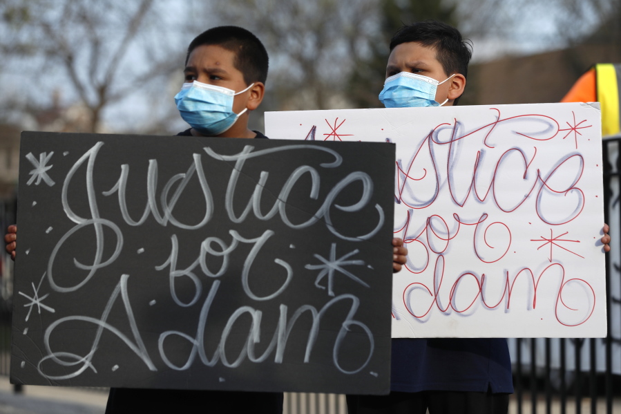FILE - In this Tuesday, April 6, 2021, file photo, Jacob Perea, 7, left and Juan Perea, 9, hold signs as they attend a news conference following the death of 13-year-old Adam Toledo, who was shot by a Chicago Police officer at about 2 a.m. on March 29 in an alley. The independent board that reviews Chicago police shootings says it will release body camera footage and other investigation materials Thursday, April 15, 2021, pertaining to the fatal shooting.