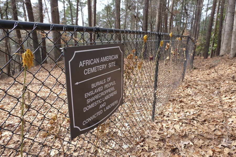 Flowers adorn a fence marking an African American cemetery site at Woodland Cemetery in Clemson, South Carolina on Sunday, Feb.  28, 2021.   Students at Clemson University who found an unkempt graveyard on campus last year sparked the discovery of more than 600 unmarked graves most likely belonging to enslaved Black people, sharecroppers and convicted laborers. The revelation has Clemson working to identify the dead and properly honor them amid a national reckoning by universities about their legacies of racial injustice.