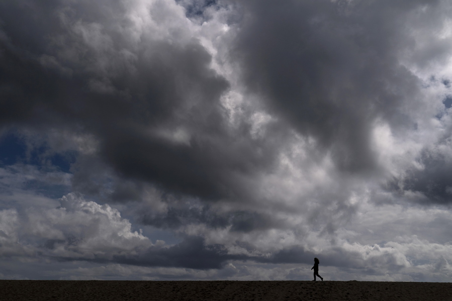 A woman strolls along the beach under rain clouds March 10 in Seal Beach, Calif. Rainstorms grew more erratic across most of the West over the past 50 years. (jae c.
