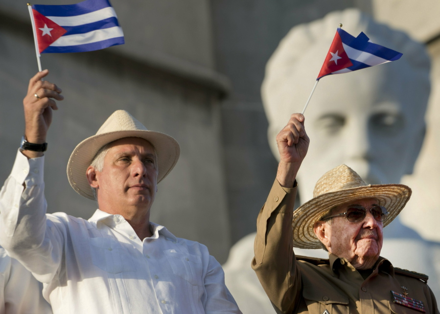 FILE - In this May 1, 2019 file photo, Cuba's President Miguel Diaz-Canel, left, and former Cuban President Raul Castro wave Cuban flags as they watch the annual May Day parade file past at Revolution Square in Havana, Cuba. On Monday, April 19, 2021, Cuba's Communist Party congress chose D~Aaz-Canel to be its leader, adding that post to the title of president he assumed in 2018, replacing his mentor Raul Castro and sealing a political dynasty that had held power since the 1959 revolution.