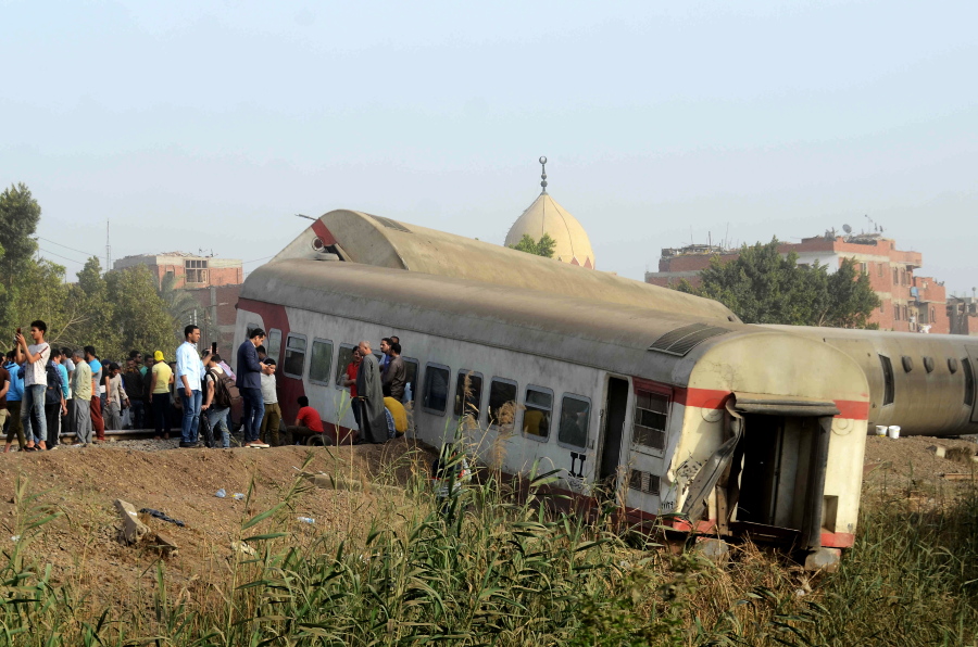 People gather at the site where a passenger train derailed injuring at least 100 people, near Banha, Qalyubia province, Egypt, Sunday, April 18, 2021. At least eight train wagons ran off the railway, the provincial governor's office said in a statement.