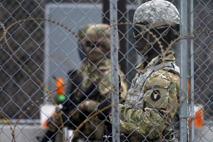National Guard members are seen through fencing and wire near the Minneapolis Police 3rd Precinct in Minneapolis on Monday, April 19, 2021, after the murder trial against former Minneapolis police Officer Derek Chauvin advanced to jury deliberations.