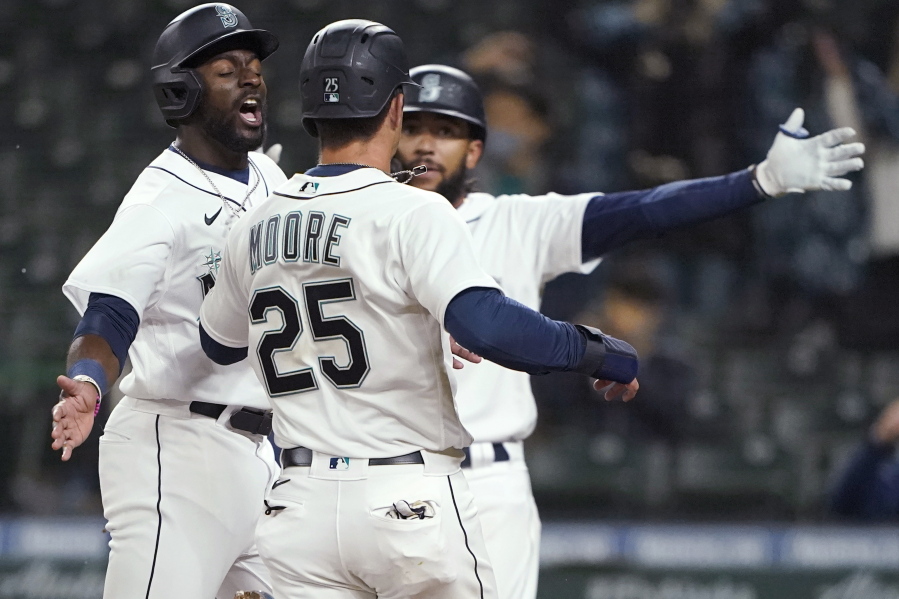 Seattle Mariners&#039; Taylor Trammell, left, greets Dylan Moore (25) at the plate after they scored during the eighth inning of the team&#039;s baseball game against the San Francisco Giants, Thursday, April 1, 2021, in Seattle. (AP Photo/Ted S.
