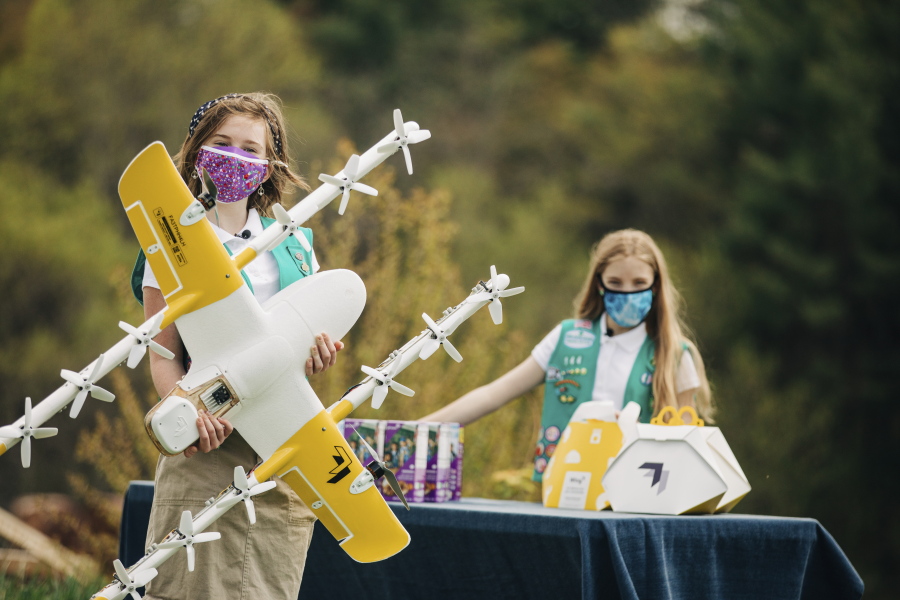 Girl Scouts Alice, right, and Gracie pose April 14 with a Wing delivery drone in Christiansburg, Va. The company is testing drone delivery of Girl Scout cookies in the area.