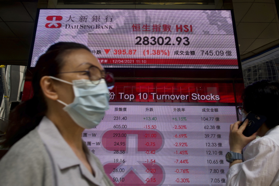 People walk past a bank&#039;s electronic board showing the Hong Kong share index at Hong Kong Stock Exchange in Hong Kong Monday, April 12, 2021. Asian shares were lower on Monday, as investors grew wary over the recent surge in coronavirus cases in many places while vaccinations are making scant headway.