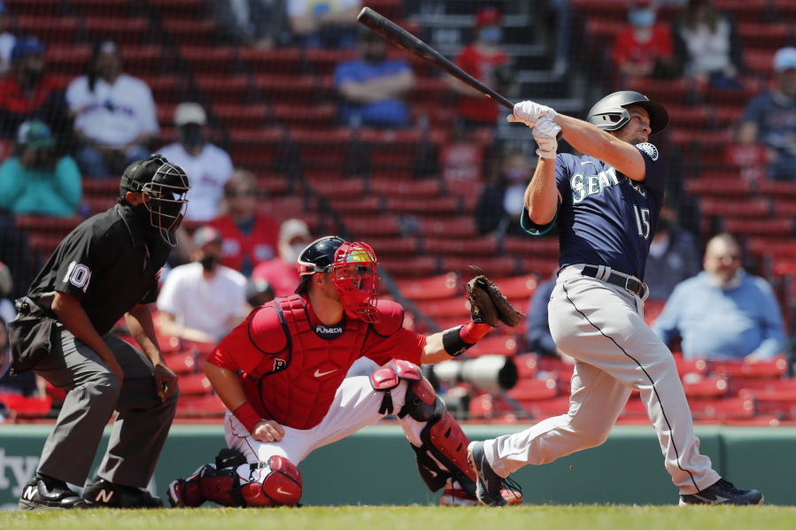 Seattle Mariners' Kyle Seager follows through on his two-run triple in front of Boston Red Sox's Kevin Plawecki during the second inning of a baseball game Saturday, April 24, 2021, in Boston.