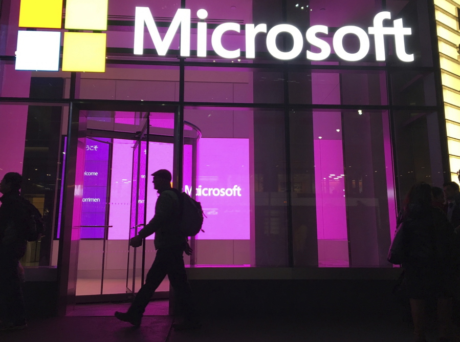 FILE - In this Nov. 10, 2016, file photo, people walk near a Microsoft office in New York. Microsoft, on an accelerated growth push, is buying speech recognition company Nuance in a deal worth $19.7 billion including debt.  (AP Photo/Swayne B.