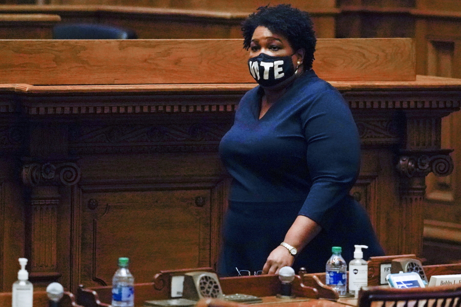 FILE - In this Monday, Dec. 14, 2020, file photo, Democrat Stacey Abrams walks on Senate floor before of members of Georgia&#039;s Electoral College cast their votes at the state Capitol in Atlanta. In a new interview with The Associated Press, voting rights advocate Abrams discussed a new state law that tightens some Georgia voting rules after Democrats carried the state in the 2020 elections.