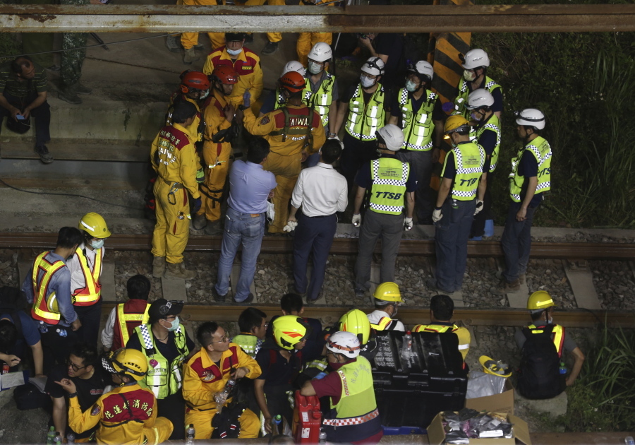 Rescue workers gather near the site of a derailed train near the Taroko Gorge area in Hualien, Taiwan on Friday, April 2, 2021. The train partially derailed in eastern Taiwan on Friday after colliding with an unmanned vehicle that had rolled down a hill, killing and injuring dozens.
