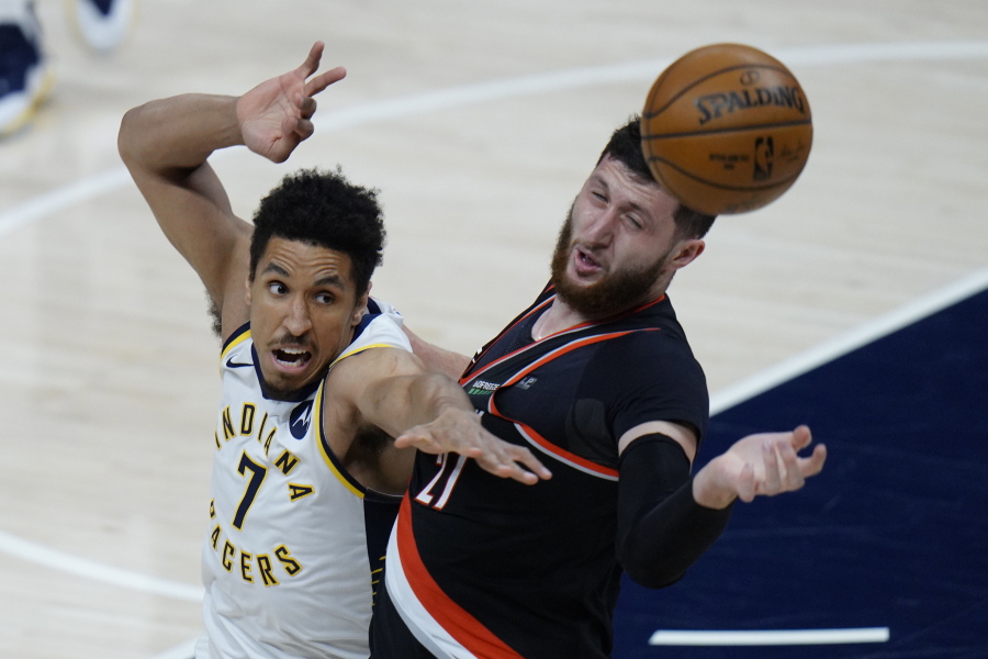Indiana Pacers guard Malcolm Brogdon, left, and Portland Trail Blazers center Jusuf Nurkic reach for a rebound during the first half of an NBA basketball game in Indianapolis, Tuesday, April 27, 2021.