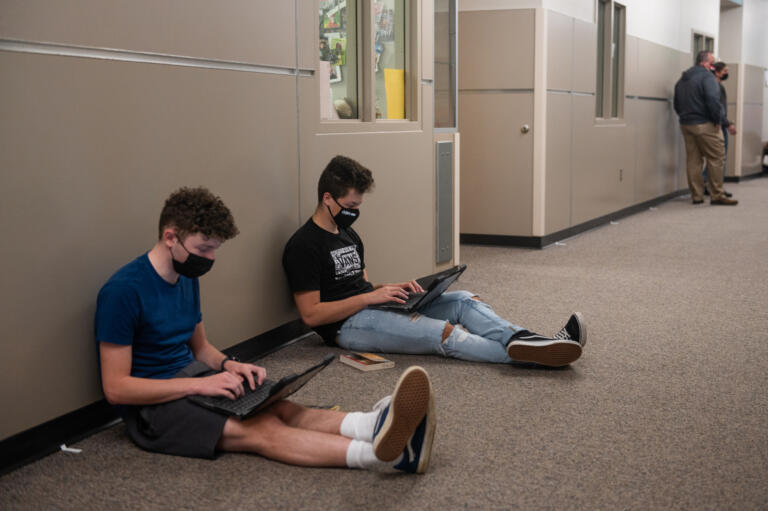 Nels Martin, left, and Tai Beaulieu work on discussion points for their book group in a hallway at Camas High School on Monday, April 19, 2021. Camas returned to four-day-a-week in-person instruction on Monday.