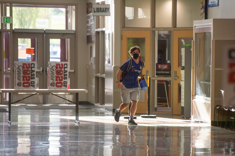A student runs to class at Camas High School earlier this month after the district switched to in-person instruction four days a week. Officials said there has been no COVID-19 transmission in schools since the change.