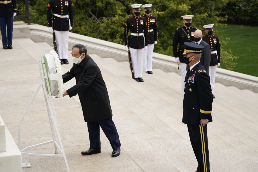 Japanese Prime Minister Yoshihide Suga places a wreath at the Tomb of the Unknown Soldier during a ceremony at Arlington National Cemetery in Arlington, Va., Friday morning, April 16, 2021, with U.S. Army Maj. Gen. Omar Jones.