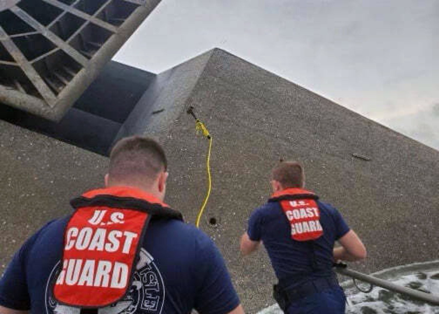 In this photo provided by the U.S. Coast Guard, Coast Guard Station Grand Isle 45-foot Response Boat-medium boat crew members attempt to throw a hammer at the hull of the SeaCor Power. The crew was attempting to make contact with potential survivors inside the vessel. . The Seacor Power, an oil industry vessel, flipped over Tuesday, April 13, 2021 in a microburst of dangerous wind and high seas. (U.S.