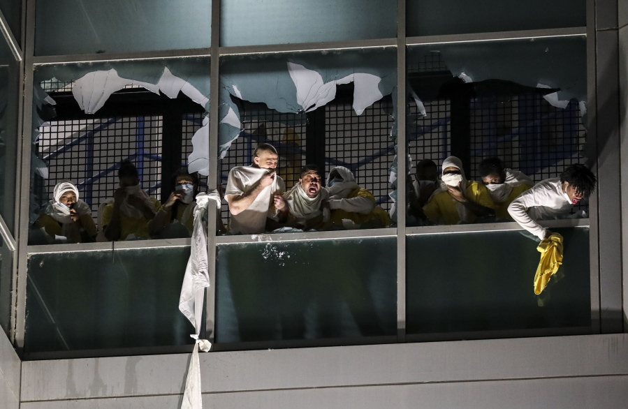 Inmates, from a second cell block, cough and try to breath through broken windows after officers deploy a chemical irritant at the St. Louis Justice Center, known as the city jail, on Sunday, April 4, 2021. Inmates broke windows, set a fire and threw debris to the ground late Sunday at a St. Louis jail that has been plagued by uprisings in recent months. (Colter Peterson/St.