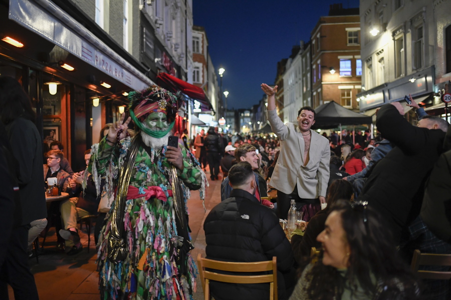 People sit at setup tables outside pubs in Soho, in London, on the day some of England&#039;s third coronavirus lockdown restrictions were eased by the British government, Monday, April 12, 2021. Pubs, shops and hairdressers have opened as lockdown restrictions are eased Monday.