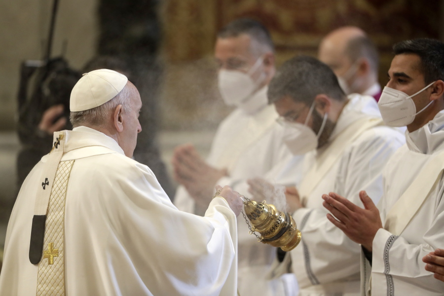 Pope Francis spreads incense during a ceremony to ordain nine new priests, standing in front of him and wearing face masks to curb the spread of COVID-19, inside St. Peter's Basilica, at the Vatican, Sunday, April 25, 2021.