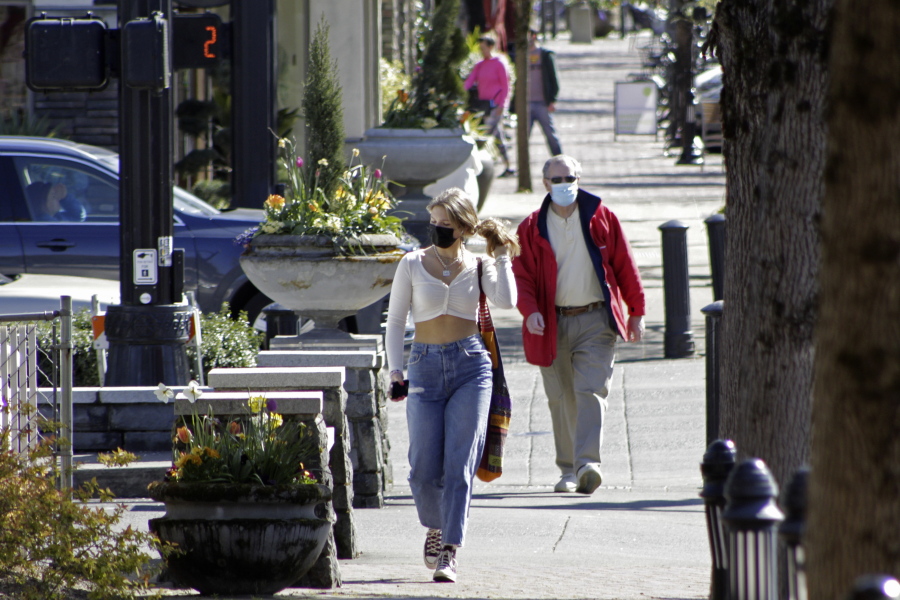 FILE - In this April 11, 2021, file photo, residents wearing masks walk in downtown Lake Oswego, Ore. Oregon Gov. Kate Brown said Tuesday, April 27, 2021 rising COVID-19 hospitalizations threaten to overwhelm doctors and she is moving 15 counties into extreme risk category, which imposes restrictions including banning indoor restaurant dining.