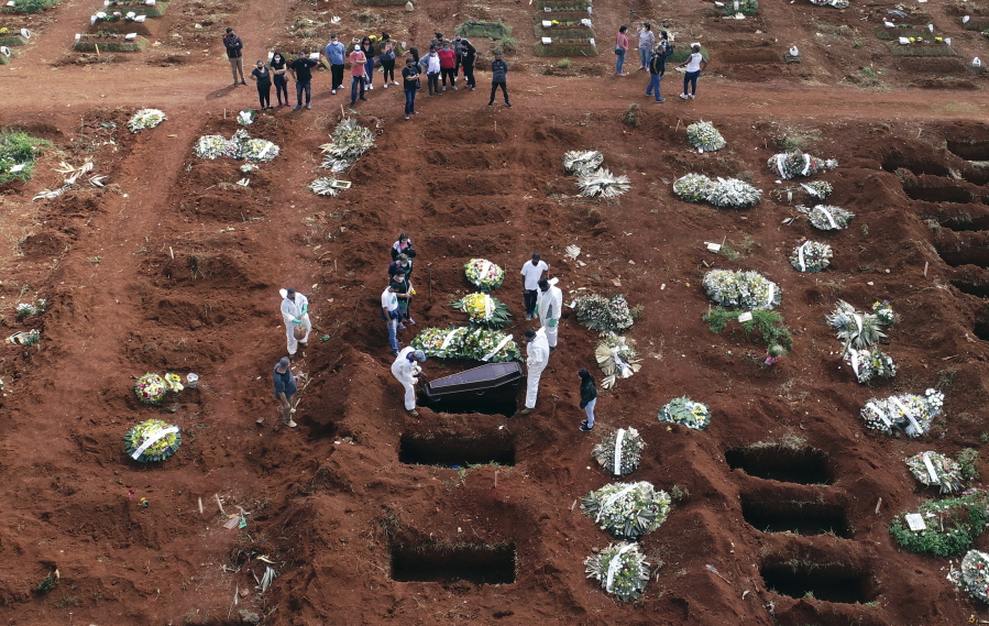 FILE - In this April 7, 2021, file photo, cemetery workers wearing protective gear lower the coffin of a person who died from complications related to COVID-19 into a gravesite at the Vila Formosa cemetery in Sao Paulo, Brazil. Nations around the world set new records Thursday, April 8, for COVID-19 deaths and new coronavirus infections, and the disease surged even in some countries that have kept the virus in check. Brazil became just the second country, after the U.S., to report a 24-hour tally of COVID-19 deaths exceeding 4,000.