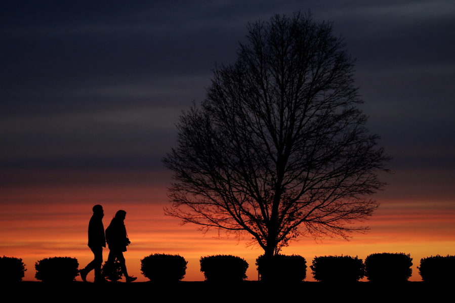 FILE - In this Monday, April 13, 2020 file photo, a couple walks alone in a Kansas City, Mo., park at sunset as stay-at-home orders continue in much of the country in an effort to stem the spread of the new coronavirus. When most of the U.S. went into lockdown in 2020, some speculated that confining couples to their homes with little to entertain themselves would lead to a lot of baby-making. But the statistics suggest the opposite happened.