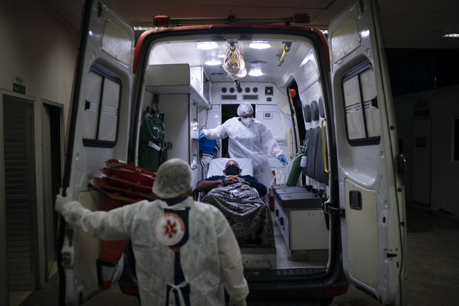 Mobile Emergency Care Service (SAMU) workers Gabrielle Carlos, top, and Joao Vericimo, move a COVID-19 patient to an ambulance as he is transferred to a municipal hospital dedicated to COVID-19 in Duque de Caxias, Rio de Janeiro state, Brazil, Tuesday, April 6, 2021.