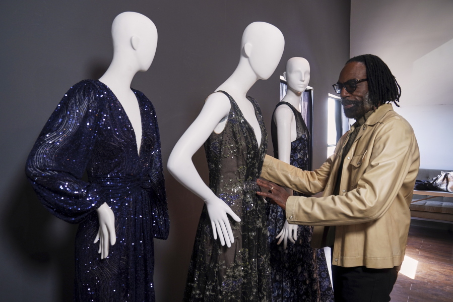 Fashion designer Kevan Hall pauses for a picture with his "Galaxy Collection" at his haute couture atelier in West Los Angeles Thursday, March 18, 2021. A year ago, Hall quickly moved away from his trademark gowns and cocktail dresses to caftans, tunics and pull-on pants. Now Hall is adding back some dressier looks, but he's eliminating the full skirts and scaling back the beading in favor of simple gowns and dresses in knit and tulle fabrics.