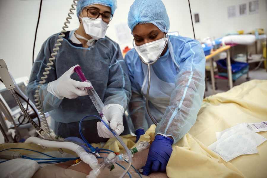 Nurses Nadia Boudra, left, and Yvana Faro, right, care for a patient inside an operating room now used for unconscious COVID-19 patients at Bichat Hospital, AP-HP, in Paris, Thursday, April 22, 2021. France still had nearly 6,000 critically ill patients in ICUs this week as the government embarked on the perilous process of gingerly easing the country out of its latest lockdown, too prematurely for those on pandemic frontlines in hospitals. President Emmanuel Macron's decision to reopen elementary schools on Monday and allow people to move about more freely again in May, even though ICU numbers have remained stubbornly higher than at any point since the pandemic's catastrophic first wave, marks another shift in multiple European capitals away from prioritizing hospitals.