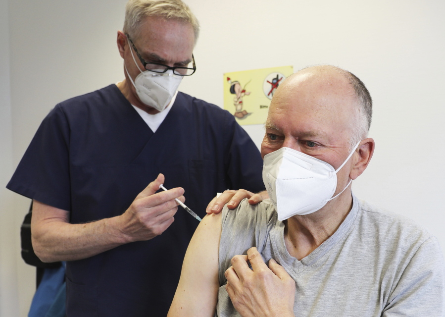 Manfred Haas, right, receives the AstraZeneca vaccine against the COVID-19 disease from his family doctor Oliver Funken in Rheinbach, Germany, Tuesday, April 6, 2021. In German federal state North Rhine-Westphalia, Corona vaccinations have started in GP surgeries.