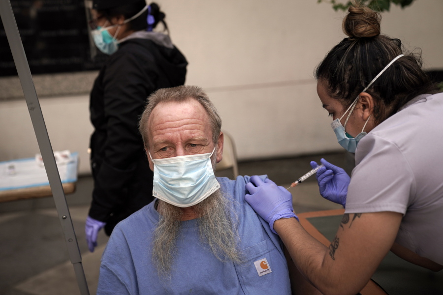 FILE - In this Feb. 3, 2021, file photo, EMT Rachel Bryant, right, administers a COVID-19 vaccine to a homeless man in the courtyard of the Midnight Mission in Los Angeles. Homeless Americans who have been left off priority lists for coronavirus vaccinations - or even bumped aside as states shifted eligibility to older age groups - are finally getting their shots as vaccine supplies increase.  (AP Photo/Jae C.