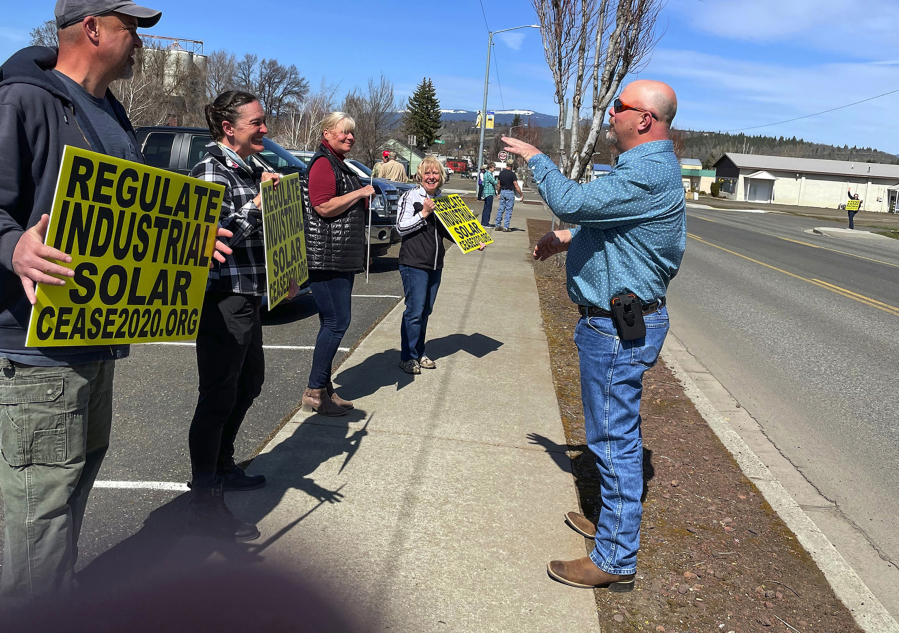 Dan Christopher, Klickitat County commissioner, talks with solar critics picketing across from the Goldendale Post Office.