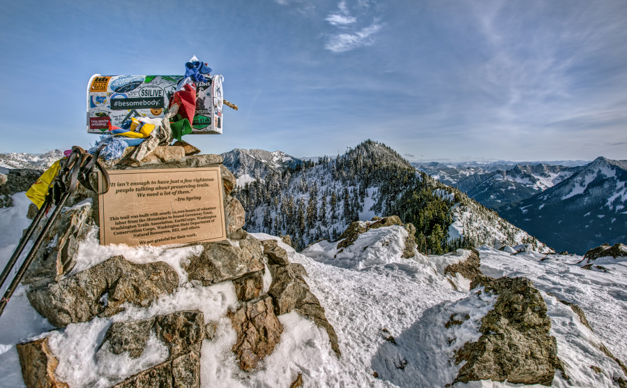 A Mailbox and Trekking Poles mark the Snowy Summit of Mailbox Peak in the Cascade Mountain Range.