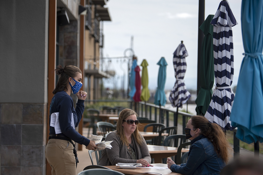 Mackenzie Samuelson, from left, of Beaches Restaurant and Bar chats with customers Andrea Pelton and Maegan Davies while stopping by their table May 6.