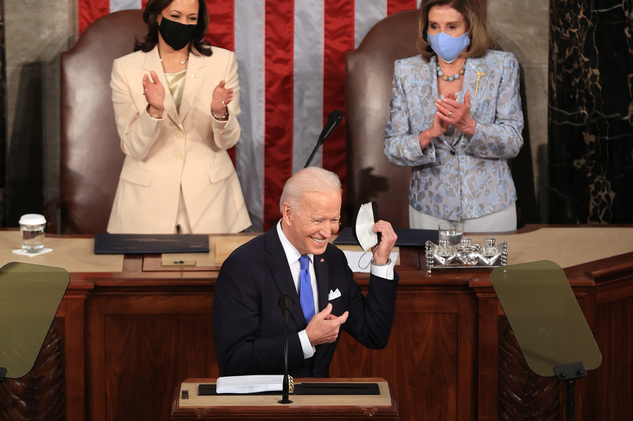 U.S. President Joe Biden removes his face mask before addressing a joint session of Congress as Vice President Kamala Harris, left, and Speaker of the House U.S. Rep. Nancy Pelosi (D-CA) look on in the House chamber of the U.S. Capitol April 28, 2021 in Washington, DC.