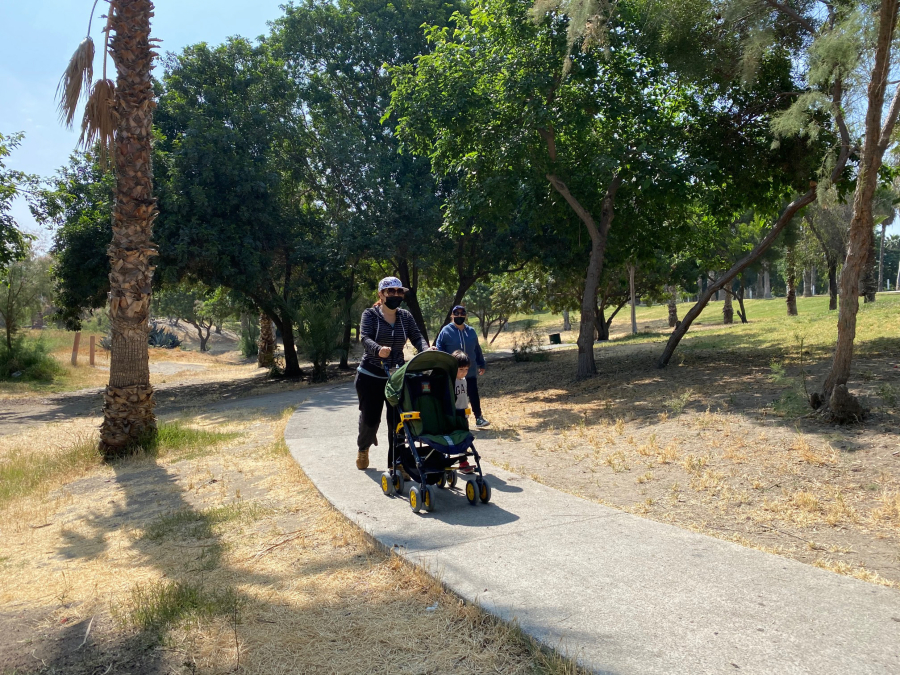 Tijuana resident Marcela Gonzalez, 44, pushes her son's stroller as he walks along side her on sunny morning in Parque Morelos on May 19, 2021.