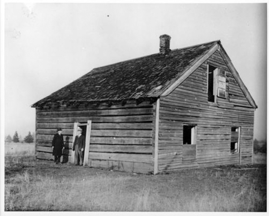 About 1920, two men in business-like dress stand near the doorway of the decaying Covington House at its original Orchards site on Covington Road. The Clark County Historical Society (then the Fort Vancouver Historical Society) and the Vancouver Women's Club planned on moving the cabin log by log in 1926 and rebuilt it about 1928 at today's location on Main Street near the Kiggins Bowl.